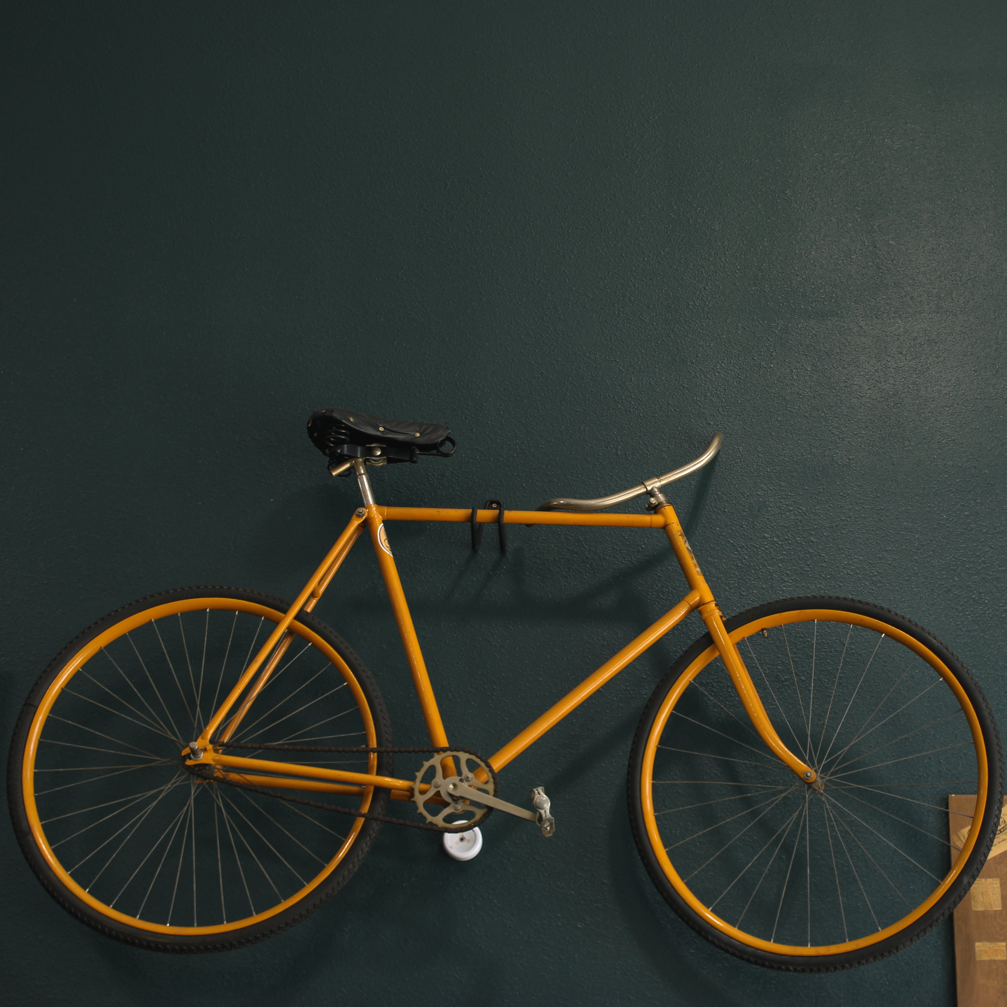 Yellow bicycle hanging on a dark green wall